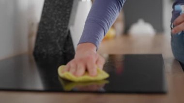 Beyaz bir kadının seramik cam tencereyi temizlemesine yakın çekim. 8K 'da kırmızı helyum kamerayla çekildi..  