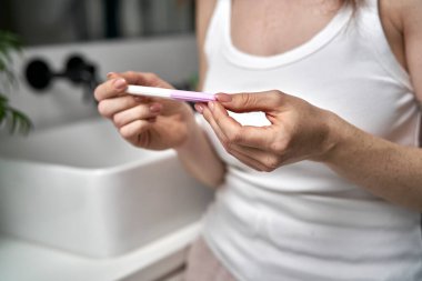 Caucasian woman in domestic bathroom looking at pregnancy test 