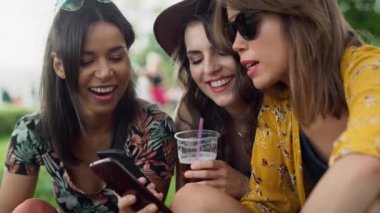 Happy women sitting on the grass and using mobile phones. Shot with RED helium camera in 8K. 