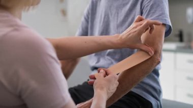 Physical therapist applying kinesio tape on patient's arm. Shot with RED helium camera in 8K.    