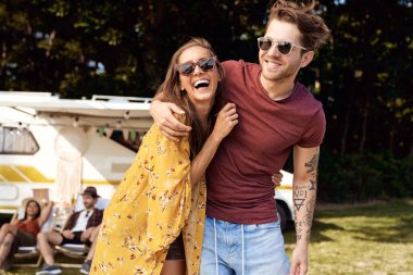 Arka planda genç bir çift sarılıyor ve kamp yapıyor.