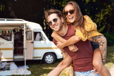 Young caucasian couple having fun and camper in the background