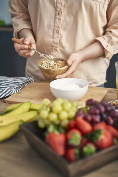 Mujer Agregando Muesli Tazón Con Yogur —  Fotos de Stock