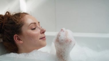 Kafkasyalı kızıl saçlı kadın banyo yapıyor. 4K 'da kırmızı helyum kamerayla çekildi..  
