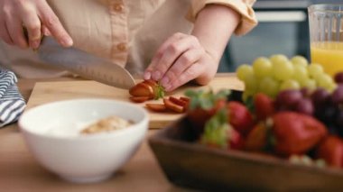 Kadın yemek için çilekleri dilimliyor.