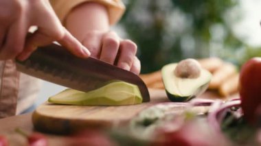 Close up of hands of woman cutting avocado at the kitchen