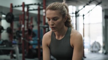 Young woman having a break at the gym while holding a bottle of water. Shot with RED helium camera in 8K. 