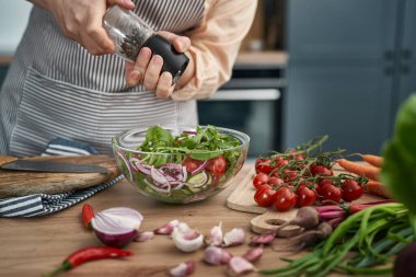 Caucasian woman seasoning the healthy and fresh salad  