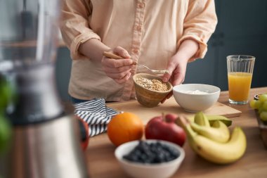 Kadın yoğurtla müsli ekliyor.