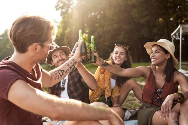 Group of young friends spending time on the camper side on drinking beer 