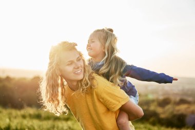 Çayırda kızları olan beyaz bir kadın oynuyor. 