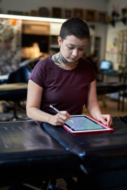 Beyaz dövmeli sanatçı stüdyoda oturuyor ve yeni bir proje yapıyor. 