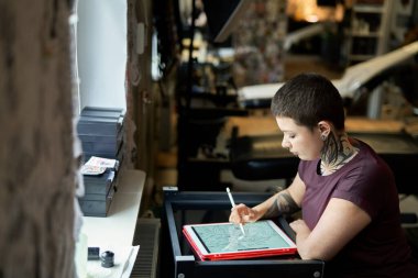 Beyaz dövmeli sanatçı stüdyoda oturuyor ve yeni bir proje yapıyor. 