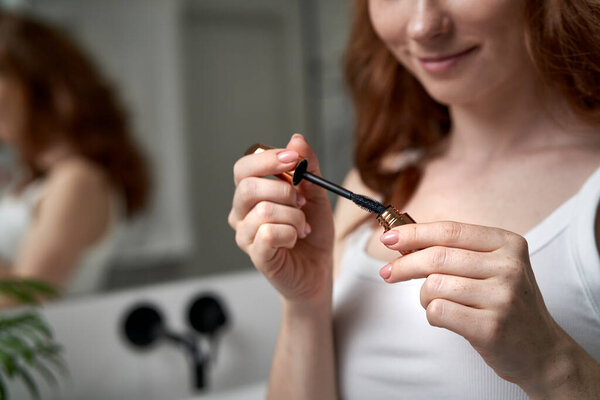 Close up of woman using mascara in the domestic bathroom