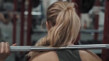 Kafkas kadının spor salonunda halter kaldırışının arka görüntüsü. 8K 'da kırmızı helyum kamerayla çekildi.. 
