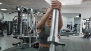 Spor salonunda halterle egzersiz yapan beyaz kadına odaklan. 8K 'da kırmızı helyum kamerayla çekildi.. 