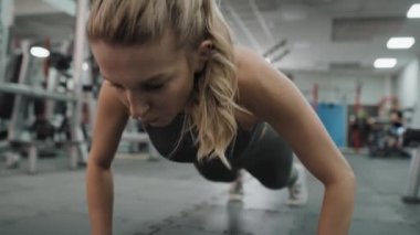 Spor salonunda dinamik şınav çeken beyaz bir kadın. 8K 'da kırmızı helyum kamerayla çekildi.. 