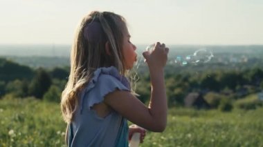 Tatlı beyaz kız çayırda köpüklerle oynuyor. 