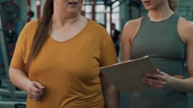 Spor salonunda kadın antrenörle konuşan şişman kadını yakından çek. 4K 'da kırmızı helyum kamerayla çekildi..   