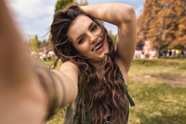 Gülümseyen beyaz kadın müzik festivalinde selfie çekiyor.