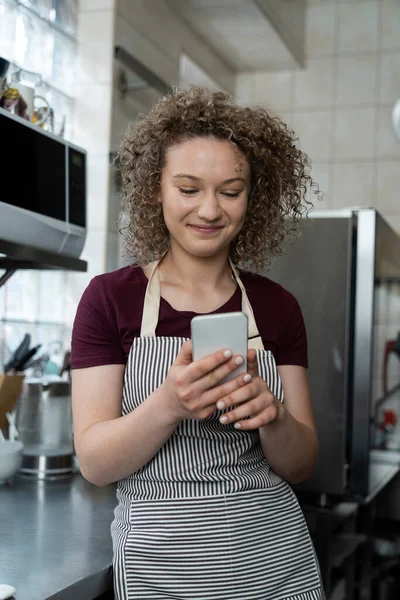 Fiatal Kaukázusi Pincérnő Telefonnal Konyhában — Stock Fotó