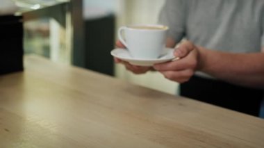 Kafkas sendromlu bir adam yürüyor ve elinde bir fincan kahve taşıyor. 8K 'da kırmızı helyum kamerayla çekildi..  