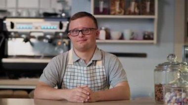 Down sendromlu beyaz bir adam yemek servisi yapıyor. 8K 'da kırmızı helyum kamerayla çekildi.. 