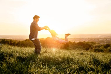Baba ve kızı çayırda birlikte oynuyorlar. 