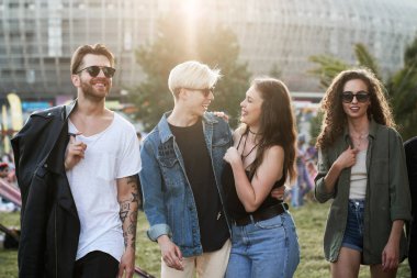 Bir grup beyaz arkadaş sohbet ediyor ve müzik festivalinde eğleniyorlar.