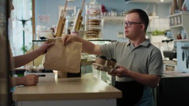 Down sendromlu beyaz bir adam kadın müşterisine yemek veriyor. 8K 'da kırmızı helyum kamerayla çekildi.. 