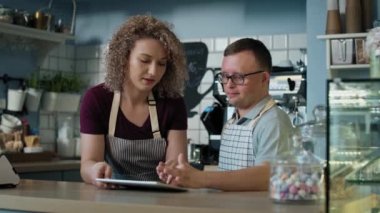 Down sendromlu beyaz bir adam dijital tabletten emir almayı öğreniyor. 8K 'da kırmızı helyum kamerayla çekildi.. 