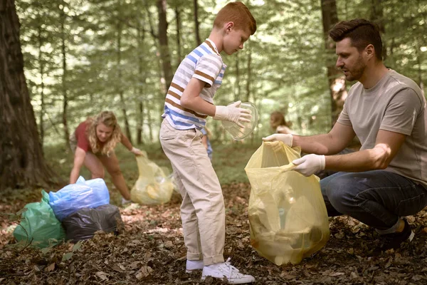 Caucasian boy cleaning forest from trashes with family