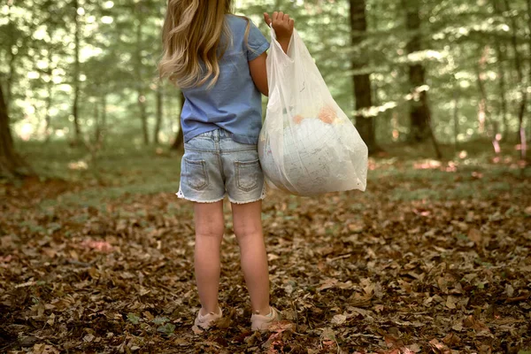 Küçük Bir Kız Ormanda Plastik Torba Içinde Dünyayı Tutuyor — Stok fotoğraf