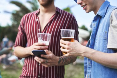 Cep telefonlu iki adam müzik festivalinde vakit geçiriyor. 