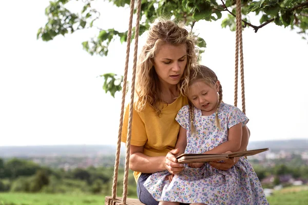 Mamá Balanceándose Con Hija Pequeña Leyendo Libro Día Verano —  Fotos de Stock