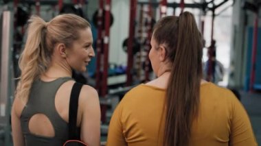 Spor salonunda müşterisiyle yürüyen fitness hocasının dikiz görüntüsü. 4K 'da kırmızı helyum kamerayla çekildi..   