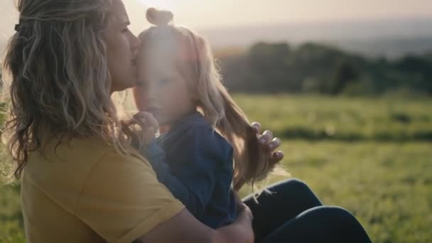 小さな娘と一緒に牧草地と結合に座ってお母さん 4KでRedヘリウムカメラで撮影 — ストック動画
