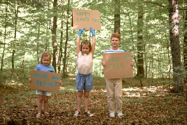 Group of kids holding posters and looking at camera in forest