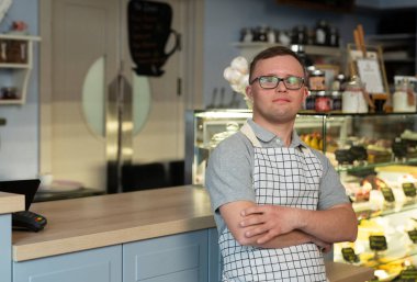 Kafeteryada çalışan, Down sendromlu beyaz bir adamın portresi.