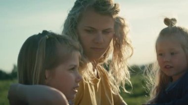 Anne ve iki küçük kızı çayırda konuşuyorlar. 4K 'da kırmızı helyum kamerayla çekildi..     