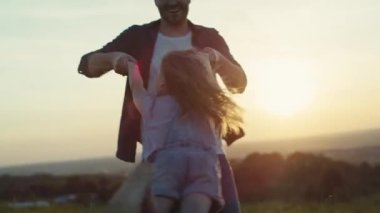 Babam gün batımında kızıyla çayırda oynuyor. 4K 'da kırmızı helyum kamerayla çekildi..  