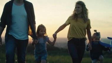 Yazın çayırda yürüyen çocuklu ebeveynler. 4K 'da kırmızı helyum kamerayla çekildi..  
