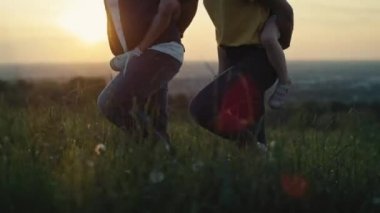 Çocukları olan ebeveynlerin yaz günü çayırda yürümesi. 4K 'da kırmızı helyum kamerayla çekildi.. 