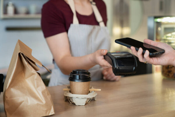 Unrecognizable client doing contactless payment in the cafe