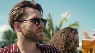 Close up of young caucasian man drinking beer from disposable cup at music festival and looking around. Shot with RED helium camera in 8K.