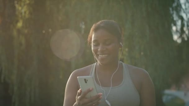 Sized African American Woman Walking Using Mobile Phone Earphones Park — Stock Video