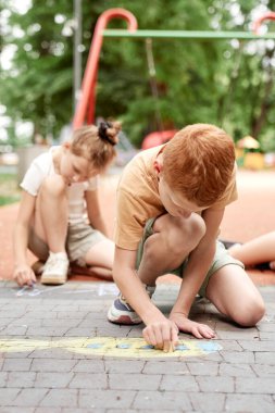 Yaz günü tebeşirle boyayan bir grup çocuk. 