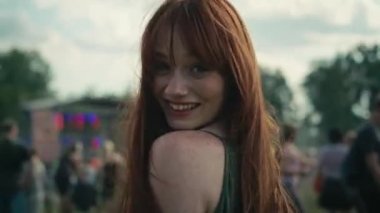 Müzik festivalinde gülümseyen kızıl saçlı, beyaz bir kadının kamera takibi. 8K 'da kırmızı helyum kamerayla çekildi.. 