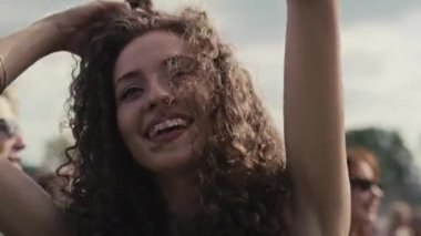 Müzik festivalinde kıvırcık saçlı beyaz bir kadının dans edişini yakından çek. 8K 'da kırmızı helyum kamerayla çekildi..