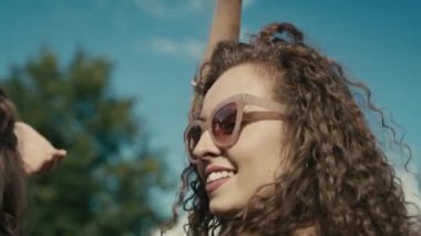 Camera tracking smiling young caucasian woman with curly hair dancing at music festival among friends. Shot with RED helium camera in 8K. 